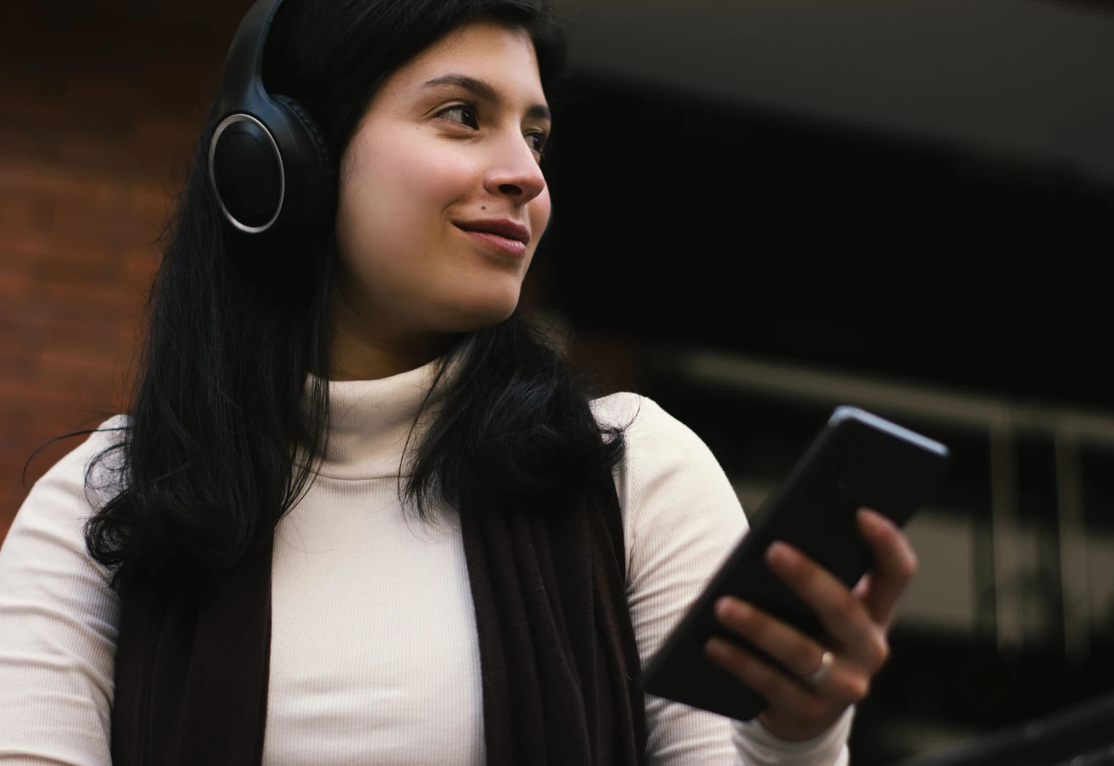 Woman using headphones and a smartphone while travelling